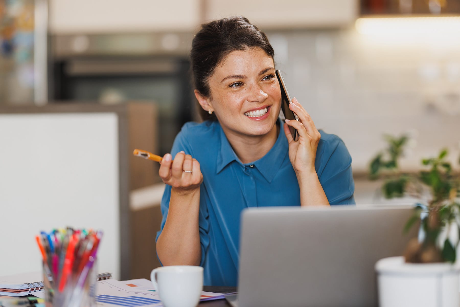 Alt text A smiling person holds a cell phone to their ear during a phone call, representing the welcoming and accessible customer service experience of contacting BankNewport and speaking directly with a person about your banking needs.