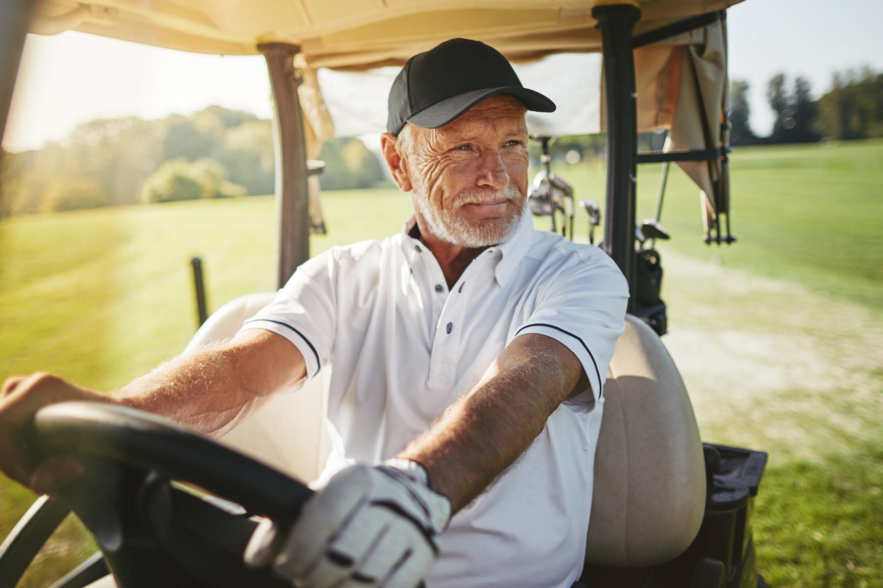 A person sits relaxed in a golf cart during a mid-round pause on a sunny afternoon golf course, representing the active, fulfilling retirement lifestyle made possible through BankNewport's investment services, investment solutions, guided wealth portfolios, wealth management programs, and retirement planning guidance available to Rhode Island investors.